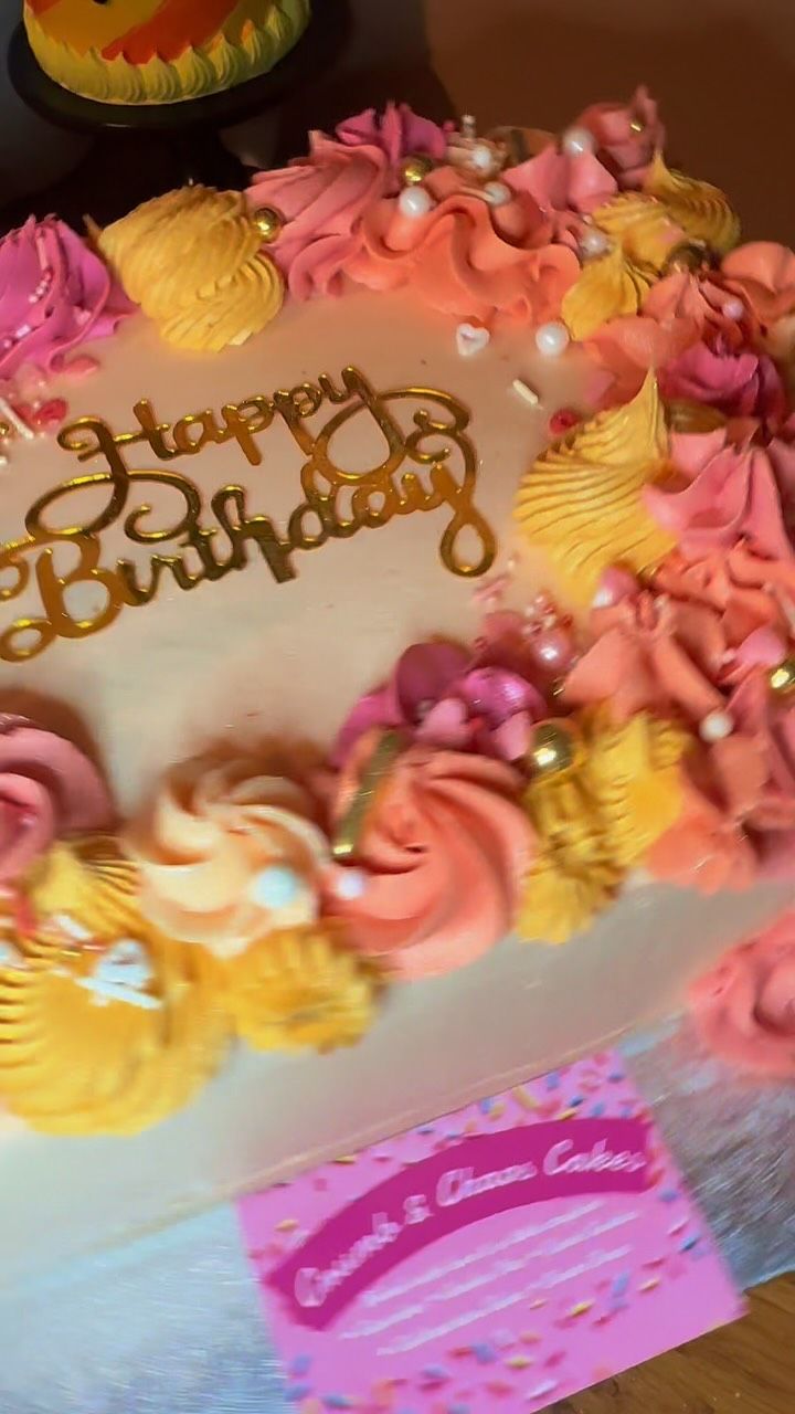 A pastel Happy Birthday cake with piped flowers and macarons