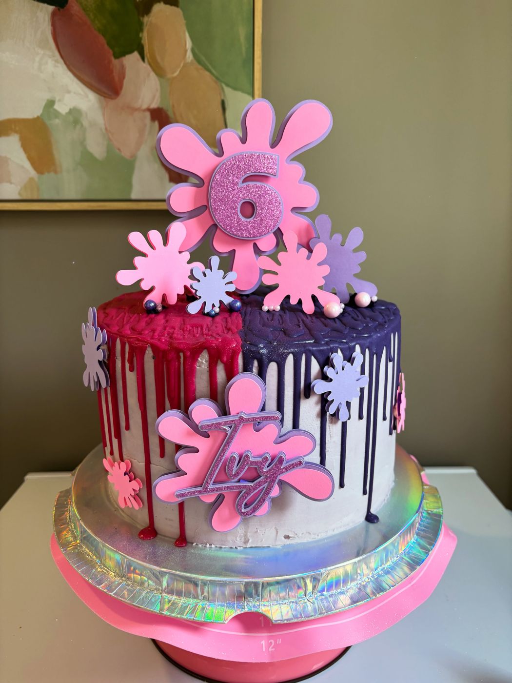 A pink drip celebration cake topped with flowers from Crumb & Chaos Cakes